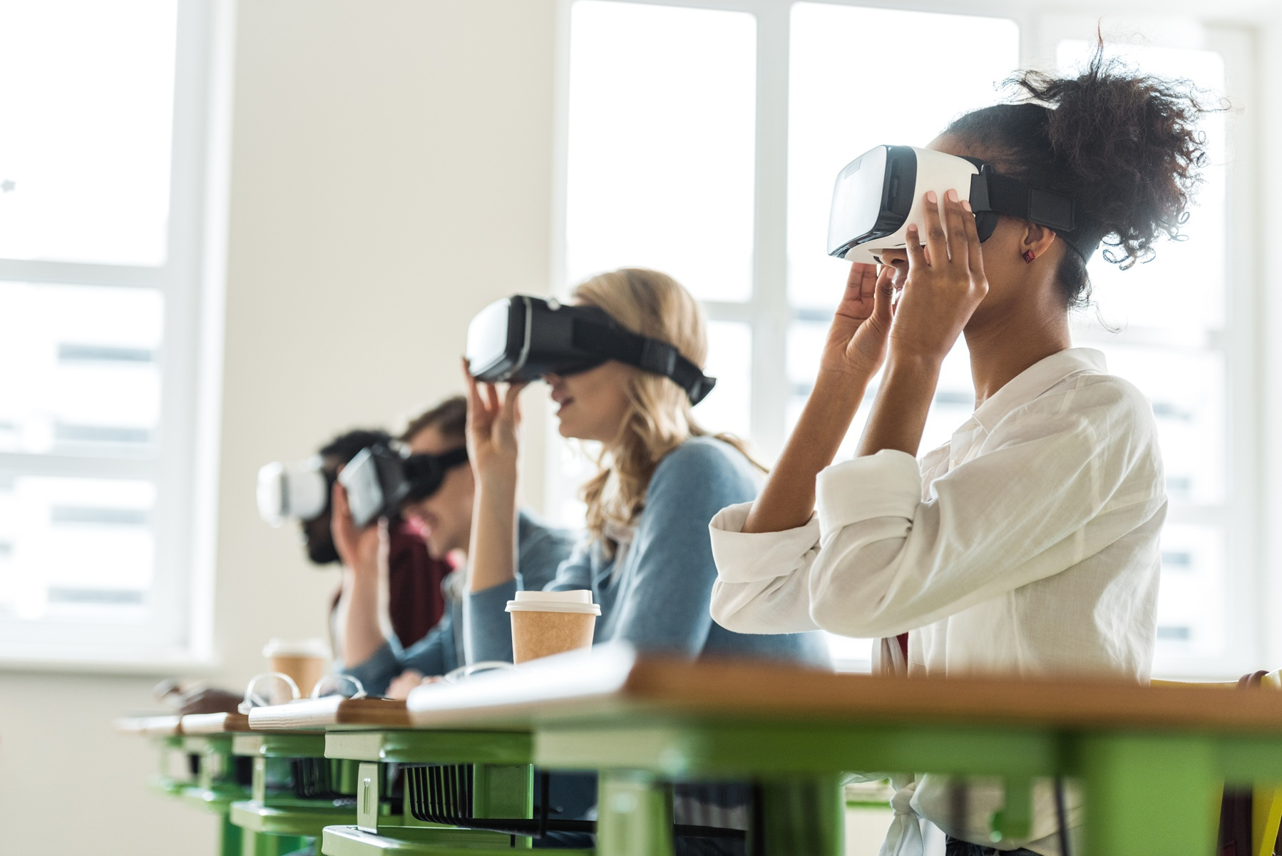 Grupa uczniów w goglach VR podczas interaktywnej lekcji w nowoczesnej pracowni szkolnej.